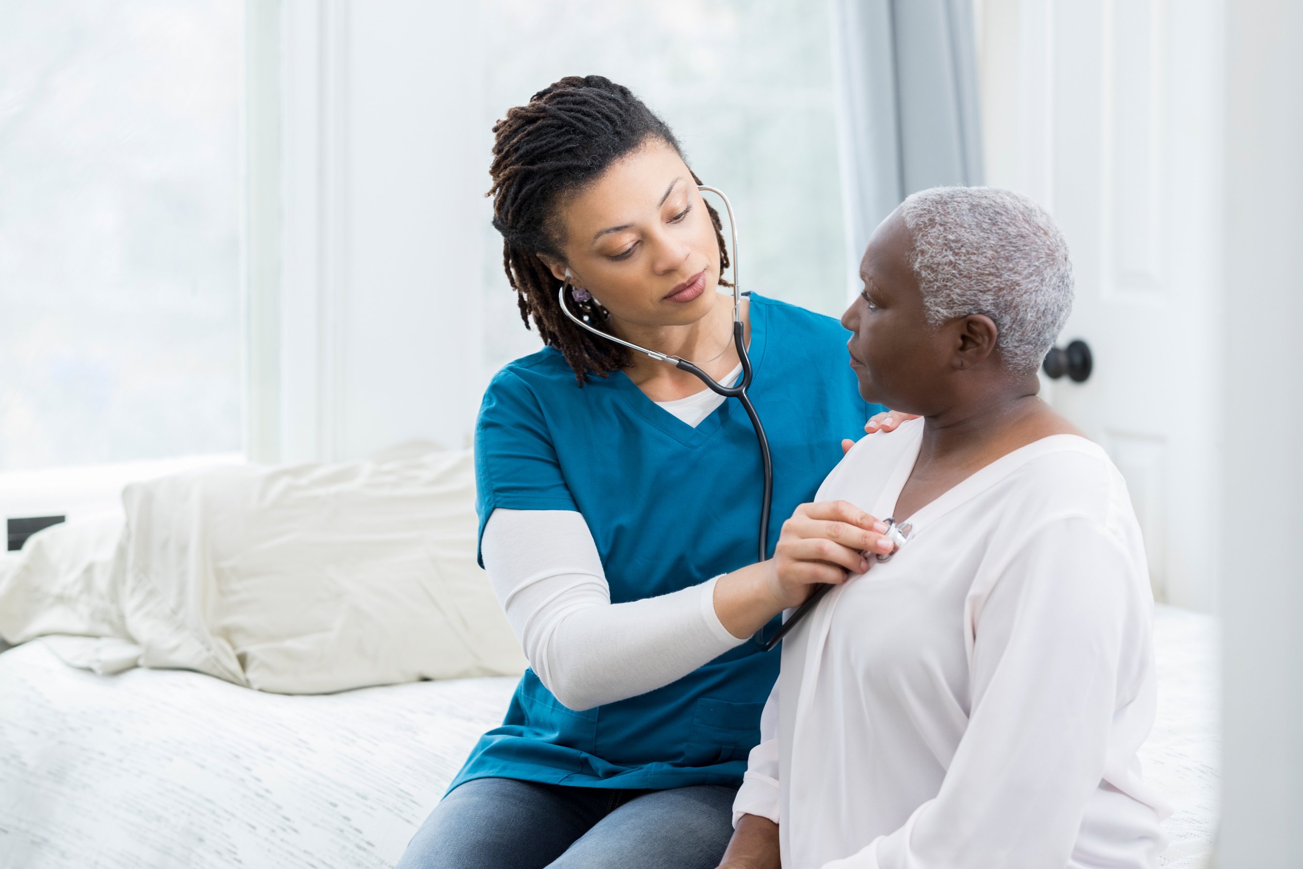 Home healthcare nurse examines elderly patient